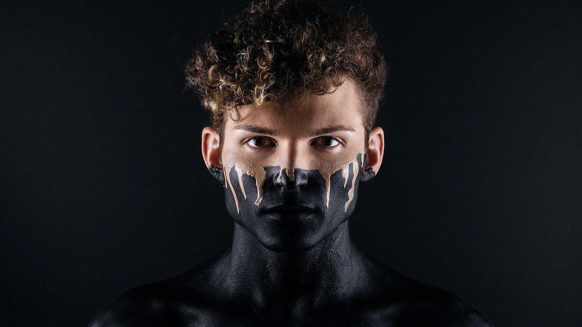 Un hombre con pintura negra en su cara obteniendo mejor protección solar facial.