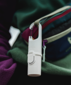 Bunker White Snow Nomad Face colgado en mochila de senderismo, protector solar mineral sostenible para actividades outdoor.