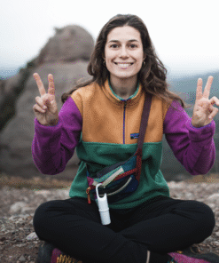 Persona sonriendo en la montaña con Nomad Face White Snow, protector solar para deportistas de montaña.