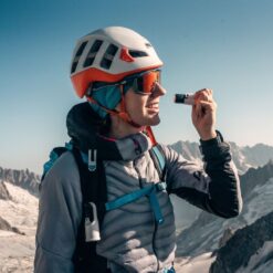 Escaladora aplicando Nomad Face White Snow protector solar en rostro, fórmula mineral sin agua.