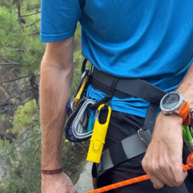Protector solar Nomad Face Yellow Sunrise fijado en equipo de escalada, ideal para actividades de montaña.