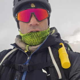Montañista con Nomad Face Bunker Yellow Sunrise en la mochila, protector solar mineral para condiciones extremas.
