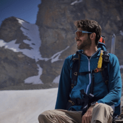 Montañista con Nomad Face Bunker Yellow Sunrise en glaciar, protector solar facial resistente al viento.