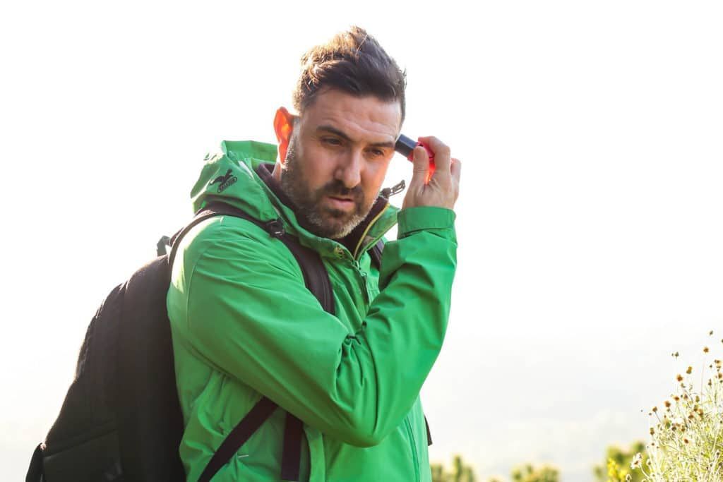 mejor-proteccion-solar-facial Un hombre con una chaqueta verde está hablando por teléfono.