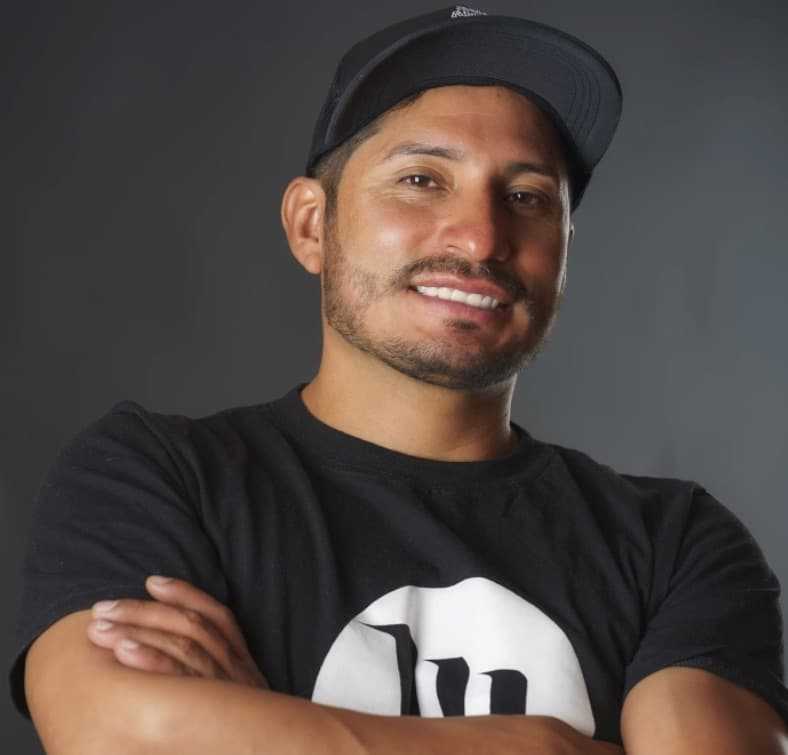 mejor-proteccion-solar-facial Un hombre con una camiseta negra con los brazos cruzados.
