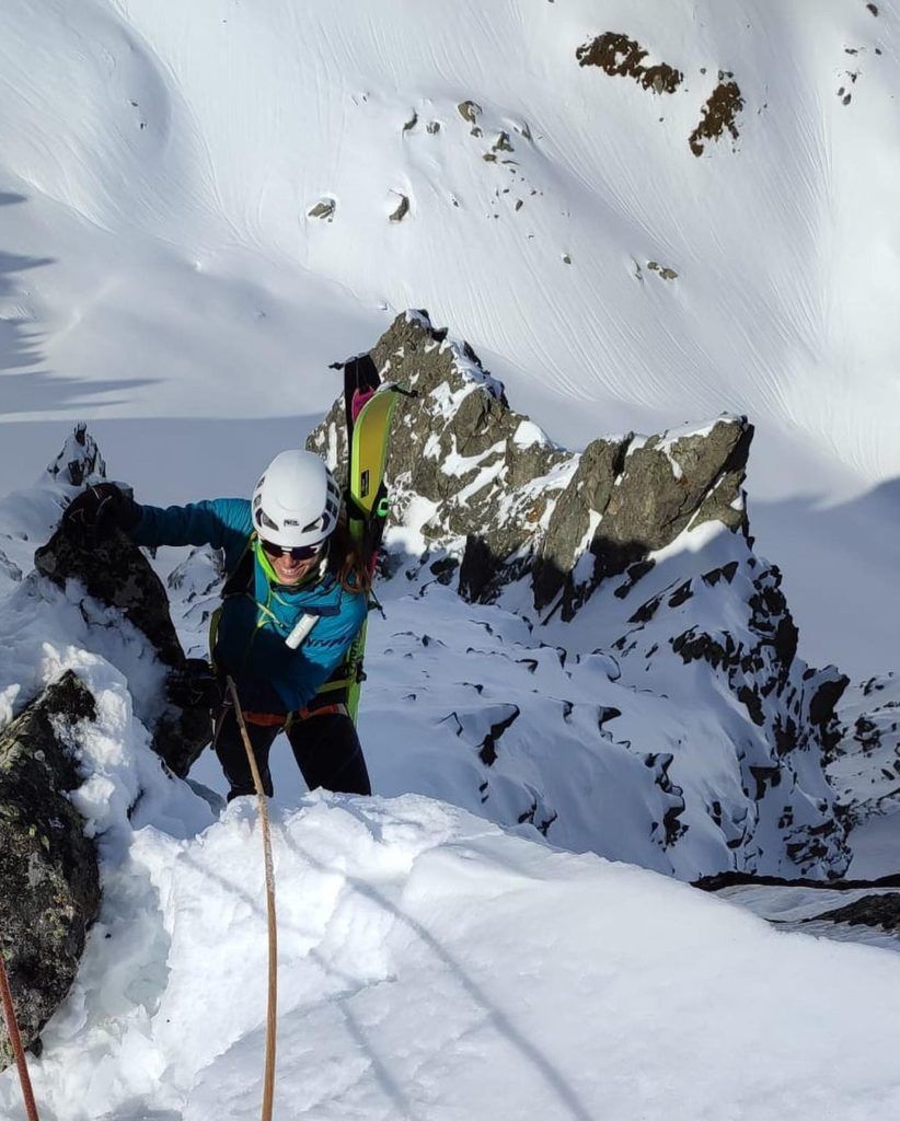 Una mujer está escalando una montaña cubierta de nieve.