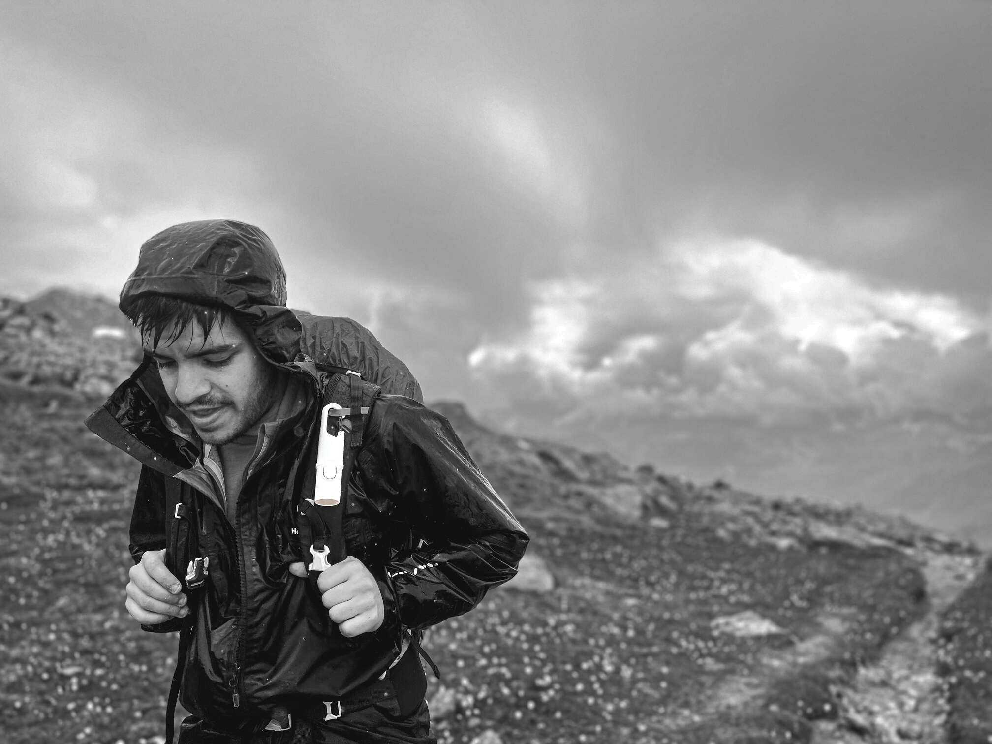 Fotografía en blanco y negro de un hombre caminando por las montañas.