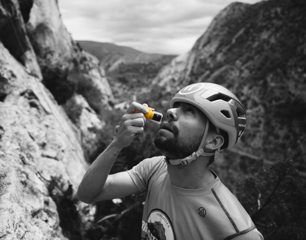 Un hombre con casco usando crema solar para escalada sin ensuciarse las manos