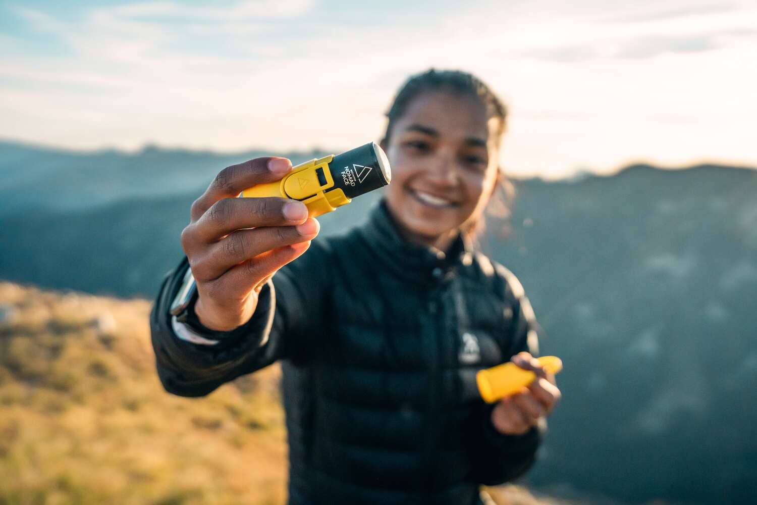 Una mujer sosteniendo un Bunker Yellow Sunrise en la cima de una montaña demostrando tener productos de protección solar máxima.