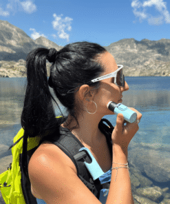 "Protector solar Nomad Face Bunker Blue Arctic – uso outdoor durante actividad de senderismo junto a un lago de montaña."