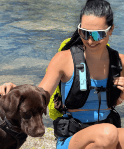 "Protector solar Nomad Face Blue Arctic – diseñado para deportistas, visible en el arnés de una excursionista junto a su perro."