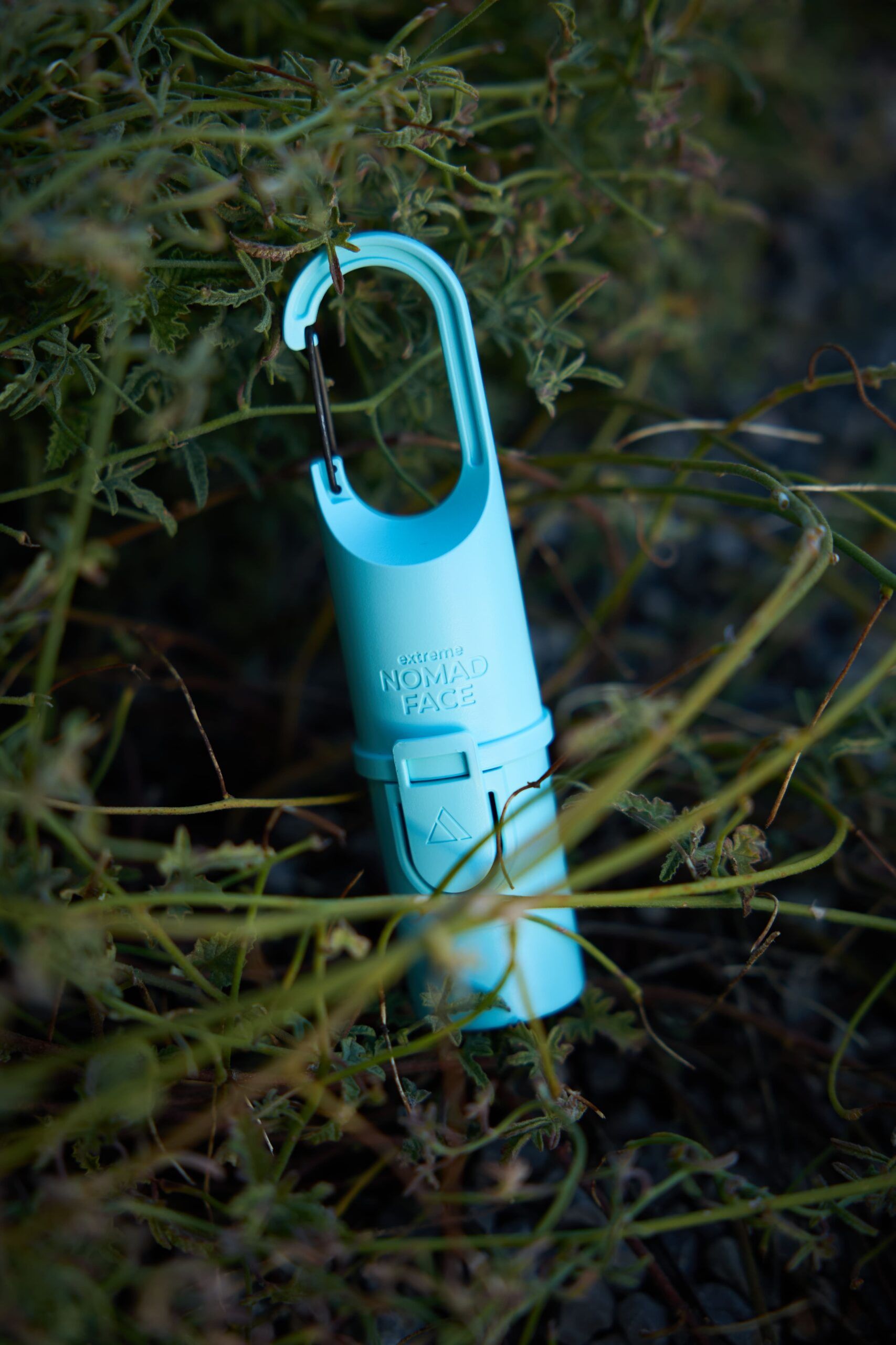 mejor-proteccion-solar-facial Un Bunker azul Arctic Nomad Face, que ofrece la mejor protección solar facial, cuelga elegantemente de una planta con su mosquetón seguro.