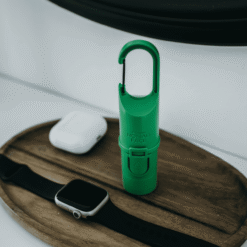 Protector solar Green Forest de Nomad Face sobre bandeja de madera junto a reloj y auriculares, ideal para el estilo de vida activo.