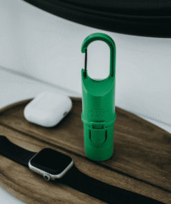 Protector solar Green Forest de Nomad Face sobre bandeja de madera junto a reloj y auriculares, ideal para el estilo de vida activo.