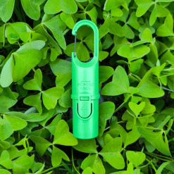 "Nomad Face Bunker Green Forest – protector solar extremo SPF50+ fotografiado sobre hojas verdes, resaltando su conexión con la naturaleza."