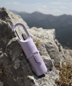 "Protector solar Nomad Face Bunker Purple Amethyst – colocado sobre una roca en alta montaña, preparado para condiciones extremas."