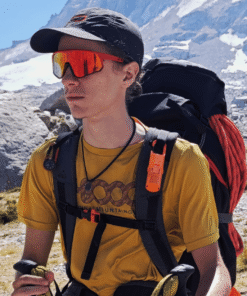 "Protector solar Nomad Face Bunker Orange Tiger – clipado en mochila de alpinista, ideal para aventuras outdoor extremas."